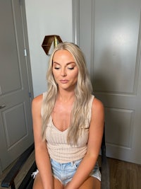 a blonde woman sitting on a chair in a room