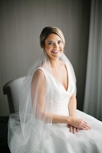 a bride in a wedding dress sitting on a chair