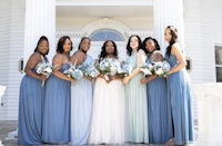 bridesmaids in blue dresses standing in front of a white house